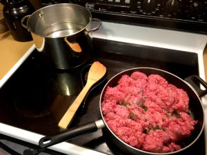 Pan of raw beef ready to cook on stove.